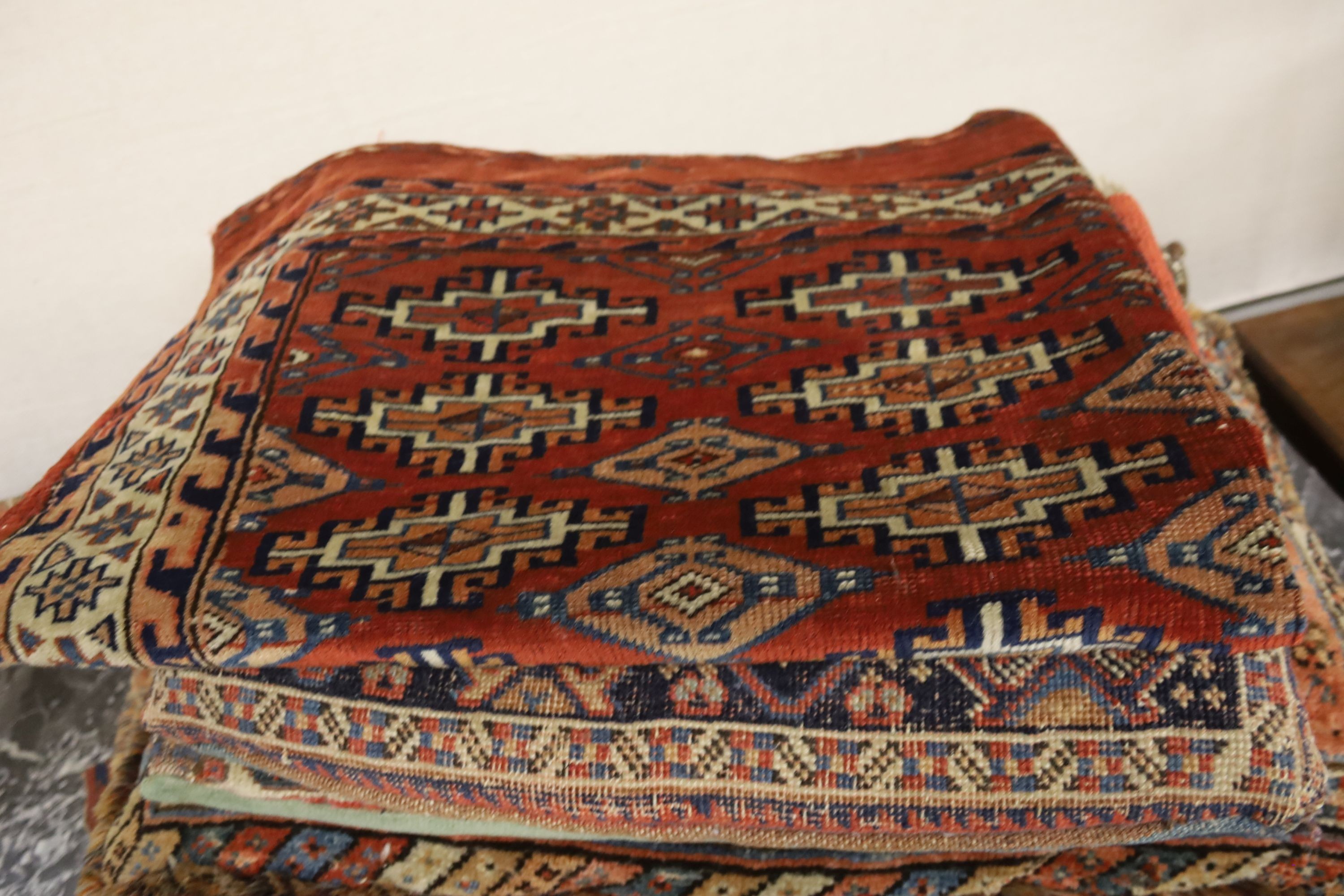 Three Bokhara rugs, four kilim-faced cushions and a small saddlebag, largest 74 x 50cm